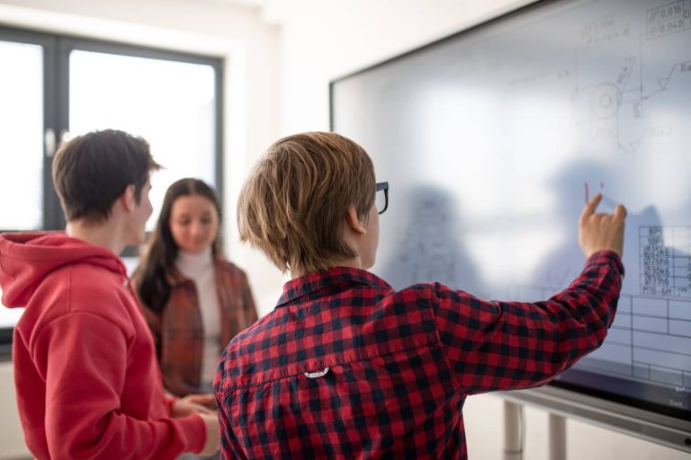 Students using a smart board in a classroom setting, engaging in interactive learning.